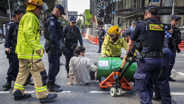 Police work to cut free protesters who had attached themselves to a barrel and blocked traffic at the intersection of George and Ann streets.