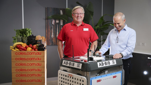Coles CEO Steven Cain and Ocado CEO Tim Steiner with one of the robots that will handle Coles' online orders. 