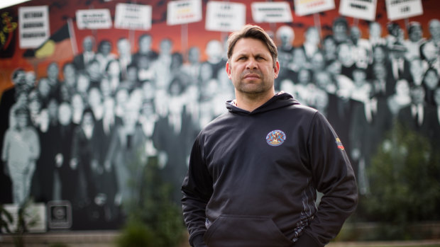 Chris Johnson in front of a mural, which features his grandmother, at the Aborigines Advancement League in Thornbury.