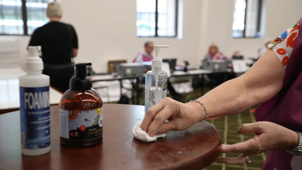 An election official uses hand sanitiser at the Brisbane City Hall polling booth on March 28.