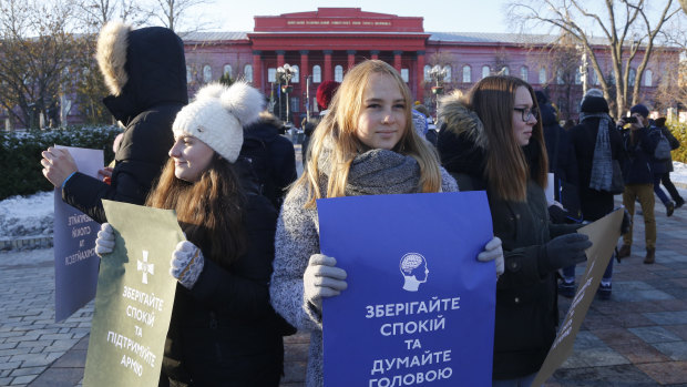 Students hold posters reading "Keep calm and think with your head" and "Keep calm support the army" in front of a university in Kiev, Ukraine.