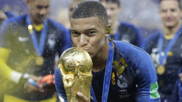 Kylian Mbappe kisses the World Cup trophy.