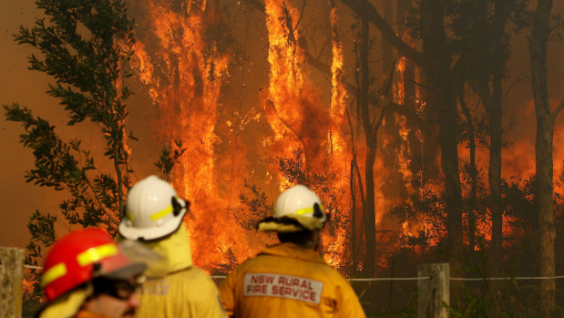 Rural Fire crews battle an out of control fire near houses along Lemon Tree Passage Road, in Salt Ash on Friday.