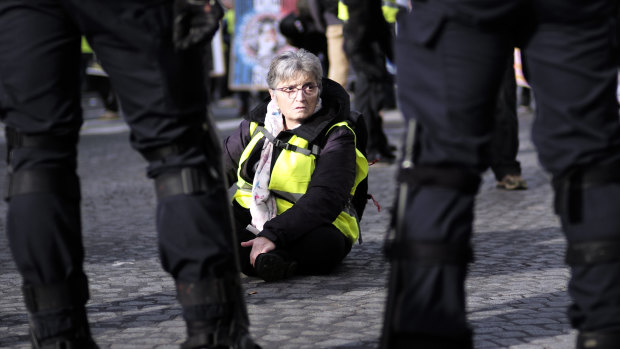 A woman sits down as other yellow vest protesters gather on the famed Champs Elysees avenue to keep pressure on French President Emmanuel Macron's government, for the 13th straight weekend of demonstrations on Saturday.