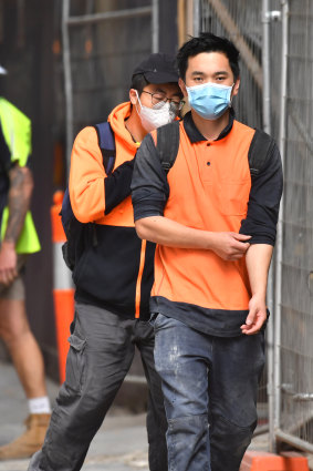 Construction workers in face masks leave a city building site.