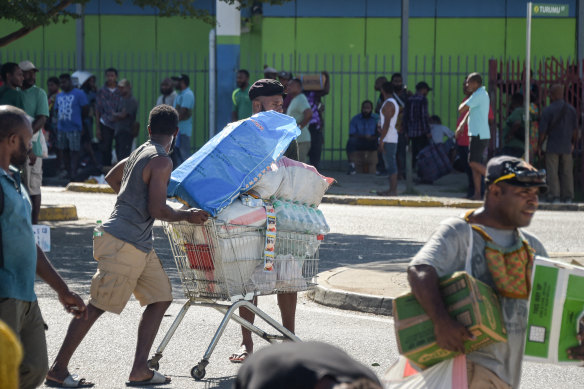 A man pushes a shopping trolley on the street as crowds leave shops with looted goods amid a state of unrest in Port Moresby on Wednesday.