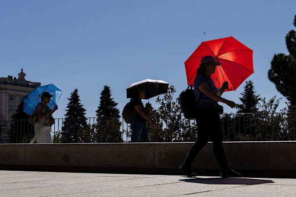 People use umbrellas as parasols to beat the heat in Madrid.
