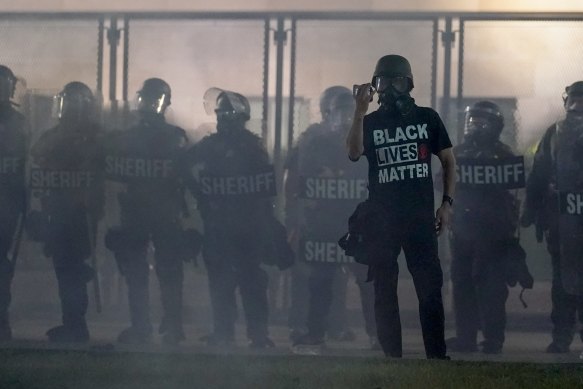 A protester holds up a phone as he stands in front of authorities in Kenosha, Wisconsin.