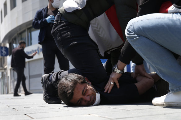 Turkish police officers arrest a demonstrator wearing a face mask for protection against the coronavirus in Istanbul last month.