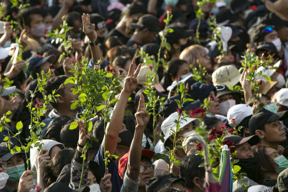 Protesters hold flowers and the three-finger salute. Thousands of anti-government protesters rallied near Government House on the anniversary of a 1973 popular uprising that led to the ousting of a military dictatorship. 