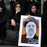 People hold up posters of Iranian President Ebrahim Raisi during a mourning ceremony for him in downtown Tehran, Iran.