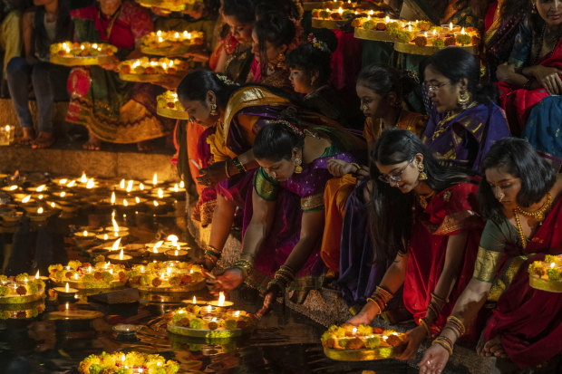 Women light oil lamps for Diwali in Mumbai.