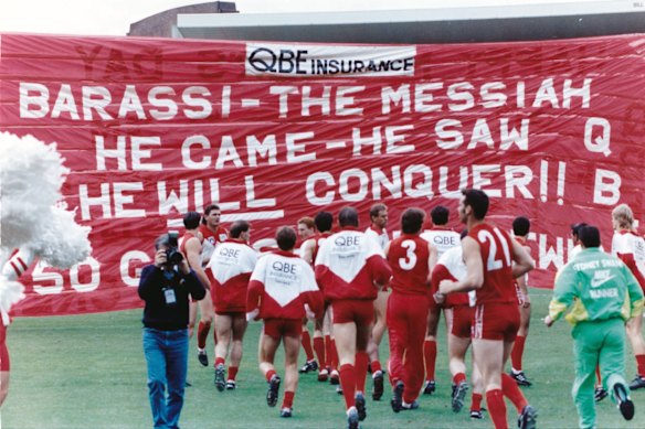 “Barassi – the messiah. He came – he saw. He will conquer!” Sydney Swans players run through a banner welcoming their new coach at the start of their game against Carlton at the SCG in 1993.