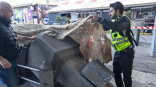 A security guard covers up the destroyed monument to John Batman at Queen Victoria Market.