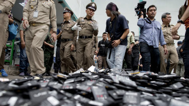 Thai National Deputy Police Chief Wirachai Songmetta, centre with white gloves, law-enforcement officers and journalists walks past a pile of mobile batteries during a raid in Bangkok on Thursday.