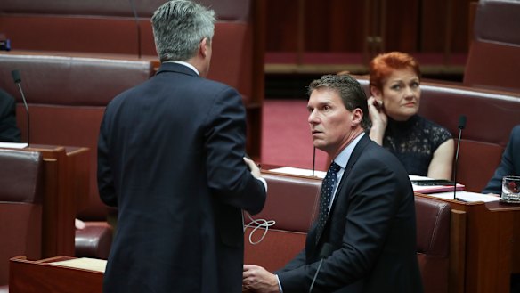 Finance Minister Mathias Cormann in discussion with Cory Bernardi and Pauline Hanson during a division in the Senate on the last sitting day of 2018. Both filibustered on the government's behalf.
