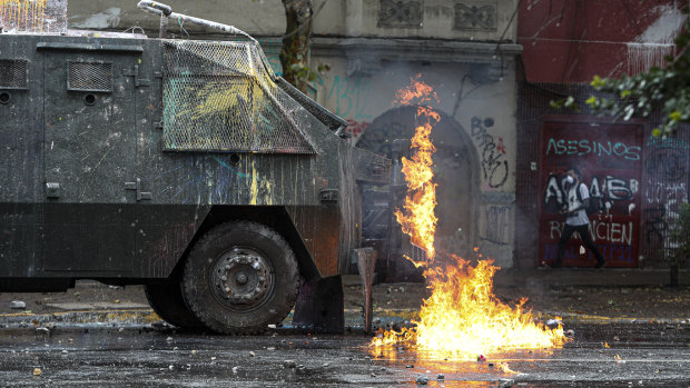 A police water cannon vehicle is hit by a gasoline bomb during clashes with anti-government demonstrators in Santiago on Monday.