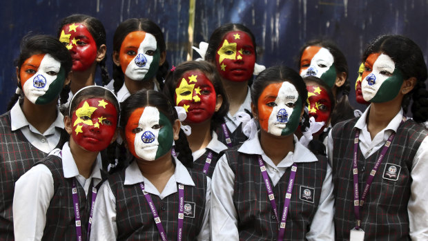 Indian school children pose with their faces painted in the colors of the national flags of India and China during an event organized to welcome Chinese President Xi Jinping on the eve of his visit in Chennai, India.