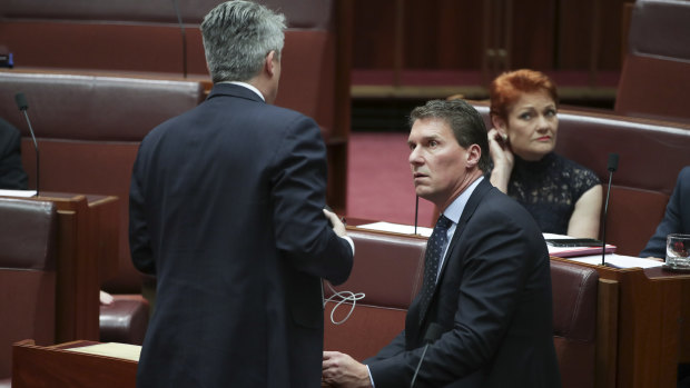 Finance Minister Mathias Cormann in discussion with Cory Bernardi and Pauline Hanson during a division in the Senate on the last sitting day of 2018. Both filibustered on the government's behalf.
