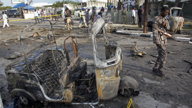 A Somali soldier walks past the wreckage of a three-wheeled motorcycle taxi at the scene of a car bomb explosion near the parliament building in the capital Mogadishu.