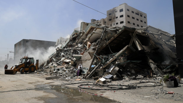 Workers clear the rubble of a building that was destroyed by an Israeli airstrike on Saturday, that housed The Associated Press, broadcaster Al-Jazeera and other media outlets, in Gaza City.