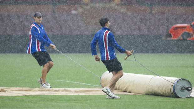 Cover drive: Groundsmen roll out the covers at the SCG earlier this month.