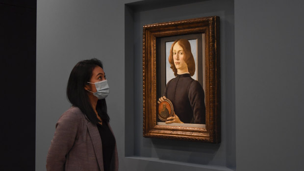 A member of the staff wears a face mask as she looks at the painting at Sotheby’s, in London.