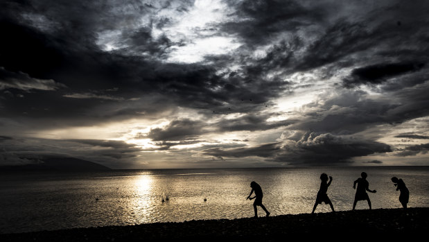 Young boys from Ambae throw stones in the direction of the volcanic island.
