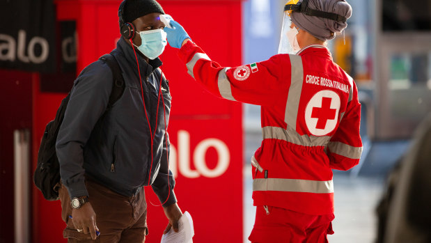 A medical worker checks the temperature of a commuter at Central Station in Milan, Italy.