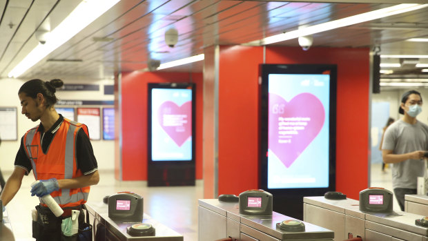 A Sydney Trains employee cleans surfaces at the turnstyles of Central Station