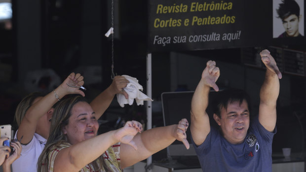 Not popular everywhere. Pedestrians flash thumbs down at National Social Liberal Party presidential candidate Jair Bolsonaro as he rides past in Brasilia's Ceilandia district. 