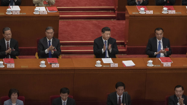 Chinese President Xi Jinping, centre, and Premier Li Keqiang, centre right, applaud after the results of a vote on a new draft security bill for Hong Kong during the closing session of the National People's Congress on Friday.