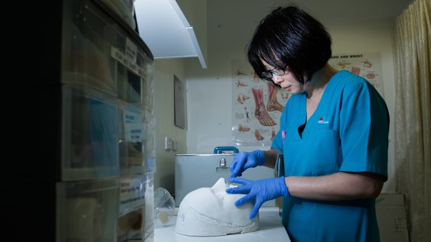 Akane Katsu carving a mask cast from the face of a patient.