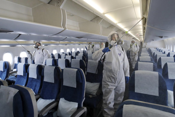 Workers wearing protective gear disinfect a plane in South Korea early in the coronavirus pandemic.