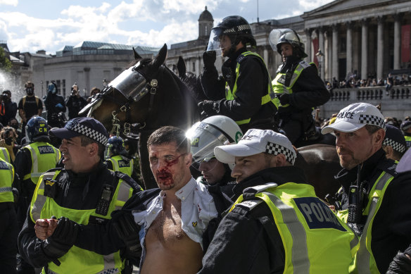 Police lead an injured man away after clashes between protesters in Trafalgar Square on June 13.