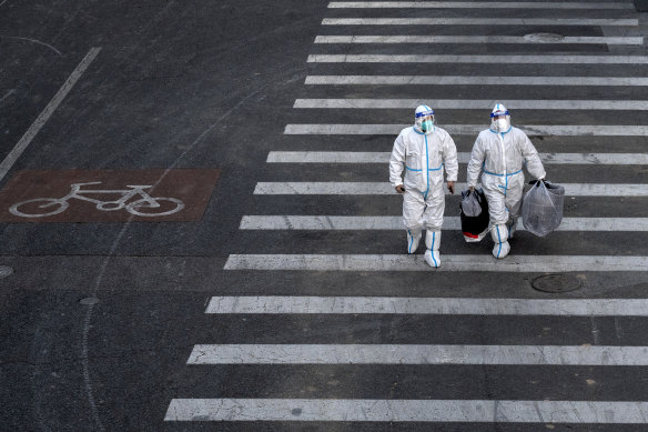 Epidemic control workers wear PPE to prevent the spread of COVID-19 as they walk across a road in an area with communities in lockdown in Beijing, China.