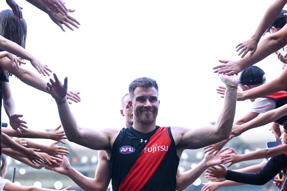 Zach Merrett high fives fans as his team leaves the MCG.