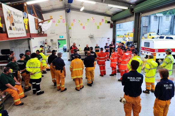 Personnel from Queensland Fire and Emergency Services, the Rural Fire Service and the State Emergency Service are briefed before assisting with the flood recovery.