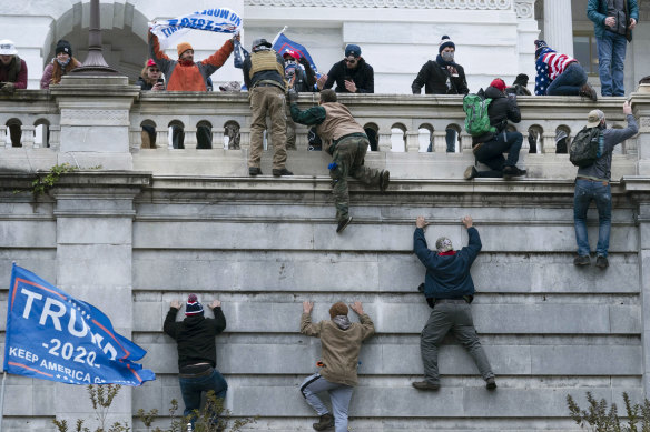 Protesters scale a wall at the US Capitol on January 6 last year.