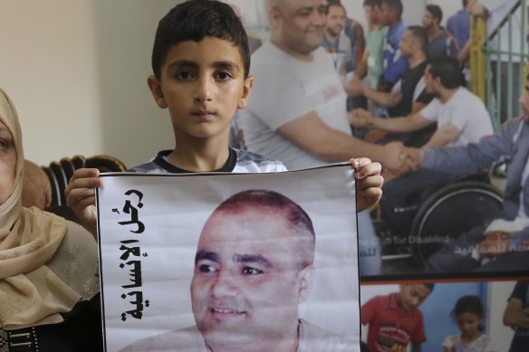 Amro el-Halabi, 7, holds a picture of his father, Mohammed, who was the Gaza director of World Vision, now found guilty of diverting sums to Hamas that exceed its total budget.
