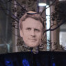 Protesters hold a banner with Emmanuel Macron’s face during a protest in Paris on Saturday.