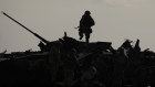 A Ukrainian solider atop a wrecked Russian tank.