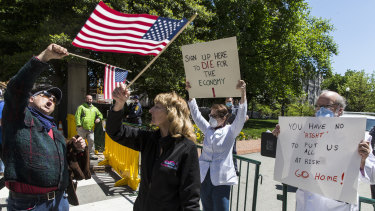 Protesters hold up signs against reopen Virginia protest, at the Virginia Capitol Square in Richmond, Virginia. 