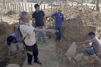 A man pointing in the foreground, who has been identified as “Lion”, a former looter of antiquities, by Cambodian officials, guides government excavators around a pillaged Khmer temple. 