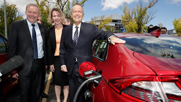 Anthony Albanese, Labor candidate for Canberra Alicia Payne and Bill Shorten view an electric car at a charging station.