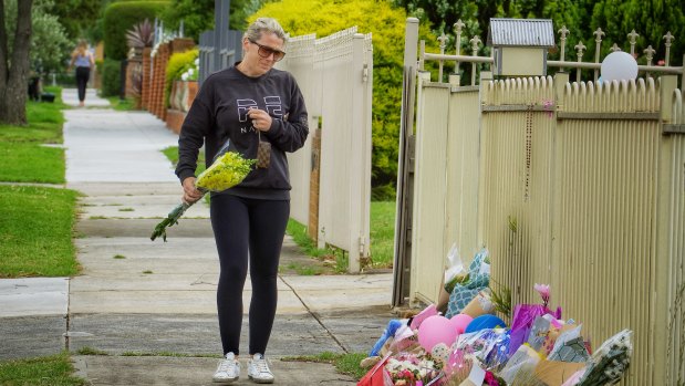 A woman drops flowers while in tears in front of the house where the bodies of the three children and their mother were found.