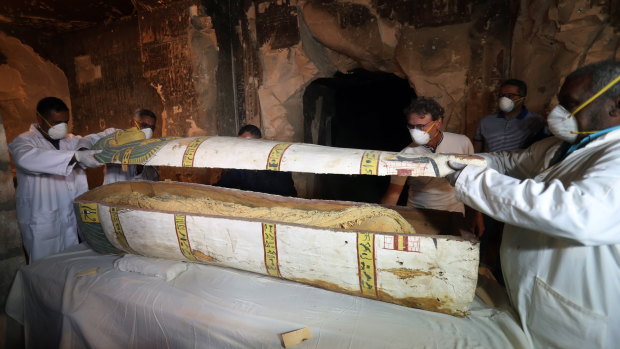 Egyptian archaeologists remove the cover of an intact sarcophagus, inside Tomb TT33 in Luxor on Saturday.