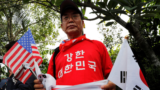 A South Korean man holds American and North Korean flags as he calls for an improvement in the human rights situation in North Korea near the Capella hotel on Sentosa island in Singapore on Tuesday.