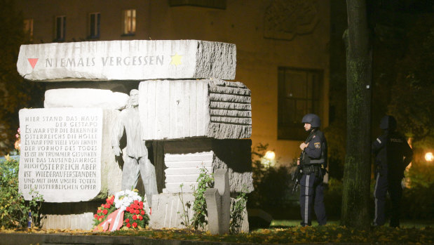 Police officers stay in position next to a memorial for victims of the Nazi era, after gunshots were heard, in Vienna.