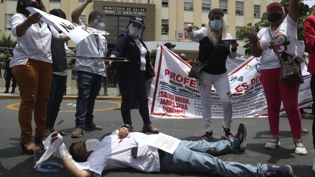 A doctor lies on the street as she allows blood to drip from her hand during a protest outside the Health Ministry headquarters in Lima, Peru, last week. The protest has now extended to a hunger strike.